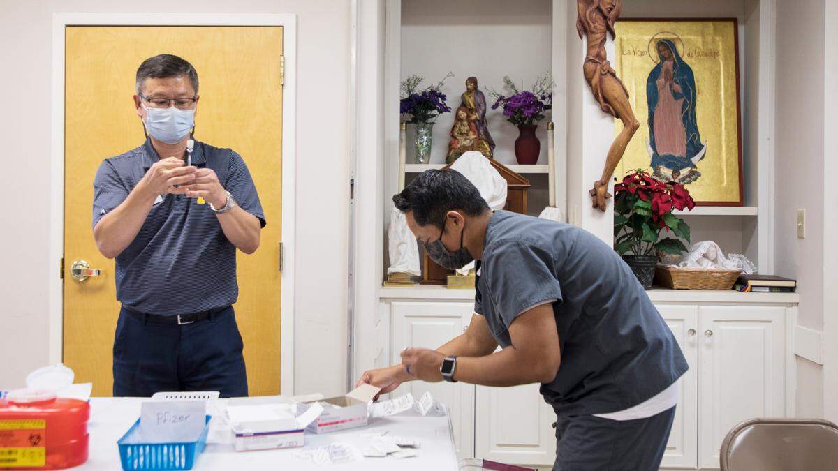 Independent pharmacists Jin Lee, left, and Alfred Catolico, right, prepare COVID-19 vaccines to be administered at an Episcopal Farm Worker Ministry clinic in Dunn, N.C. on Sept. 4, 2021. The pair own DJ’s Pharmacy in Cary, N.C. and volunteer at rural vaccine clinics on weekends.
