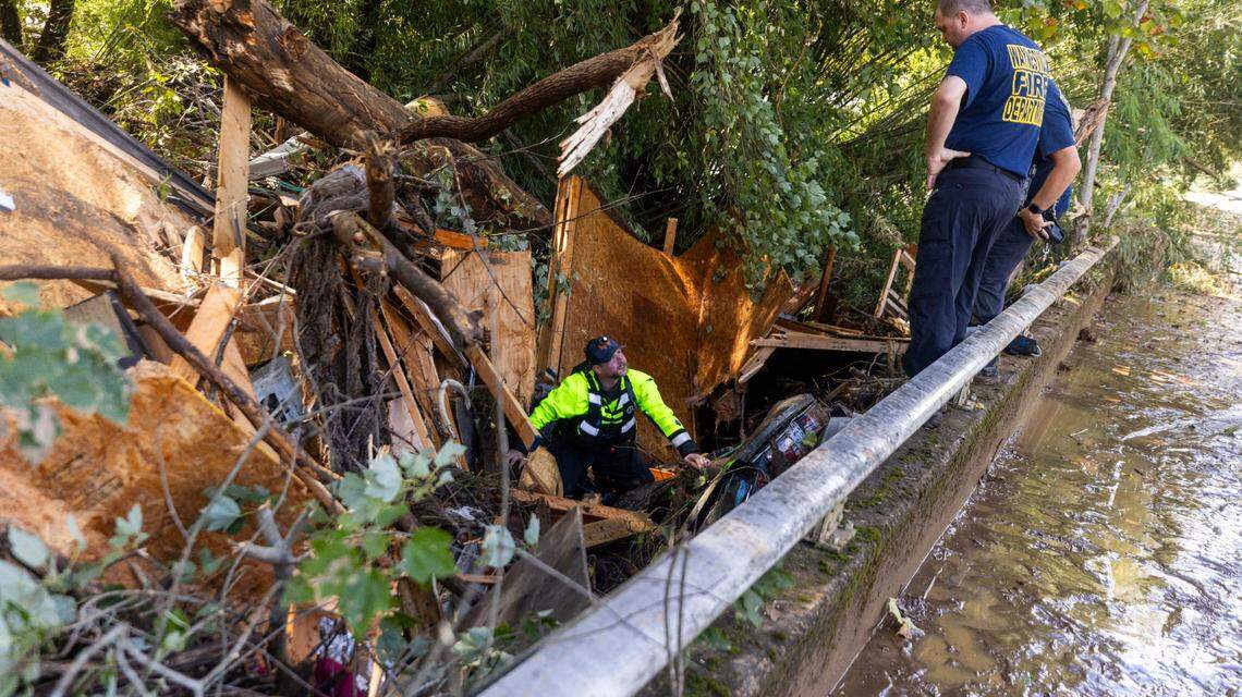 Waynesville firefighters search a car that was pinned by debris under a bridge on Richland Creek in Waynesville on Friday, Sept. 27, 2024 as the remnants of Hurricane Helene caused flooding, downed trees, and power outages in western North Carolina.