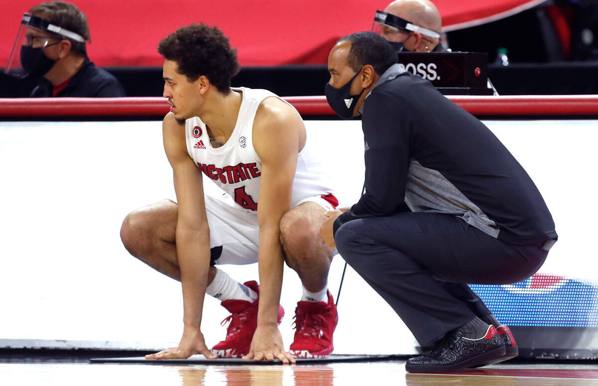 N.C. State’s head coach Kevin Keatts crouches next to Jericole Hellems (4) as Hellems waits to enter the game during the second half of N.C. Stateís 69-50 victory over Campbell at PNC Arena in Raleigh, N.C., Saturday, Dec. 19, 2020.