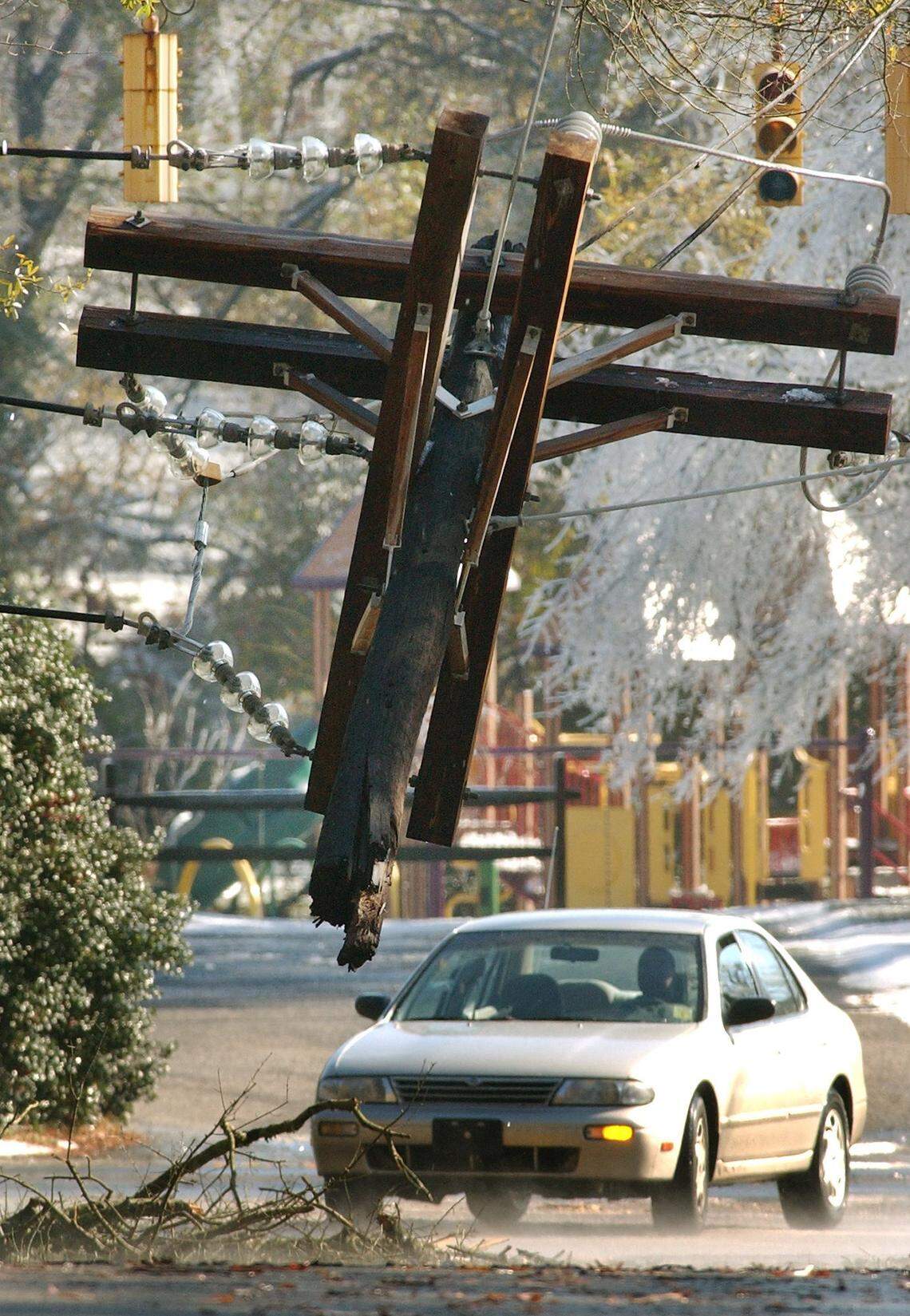 A driver decides whether or not to chance driving under broken power lines near Forest Hill Park Friday after the devastating ice storm. Line problems such as this promise to make the recovery more difficult for the thousands stranded in their homes without power.