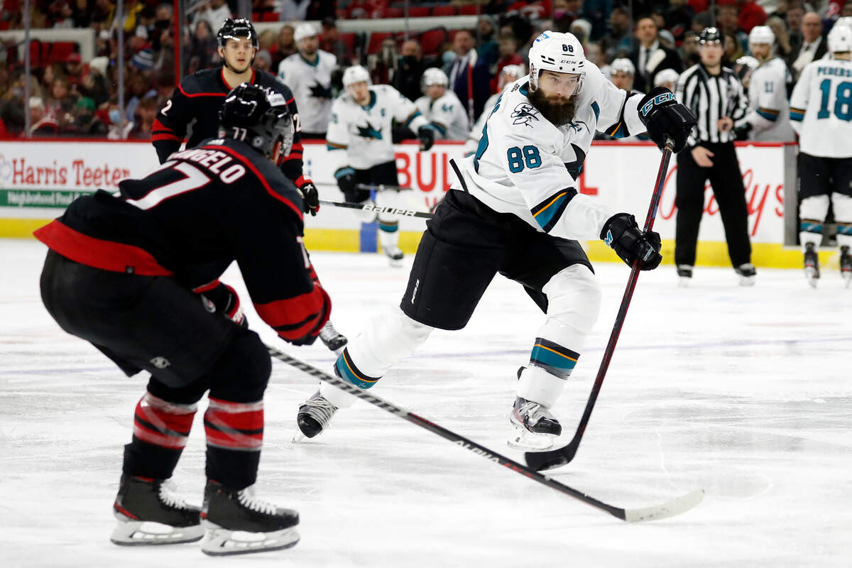 San Jose Sharks’ Brent Burns (88) shoots the puck with Carolina Hurricanes’ Tony DeAngelo (77) nearby during the third period of an NHL hockey game in Raleigh, N.C., Sunday, Jan. 30, 2022. (AP Photo/Karl B DeBlaker)
