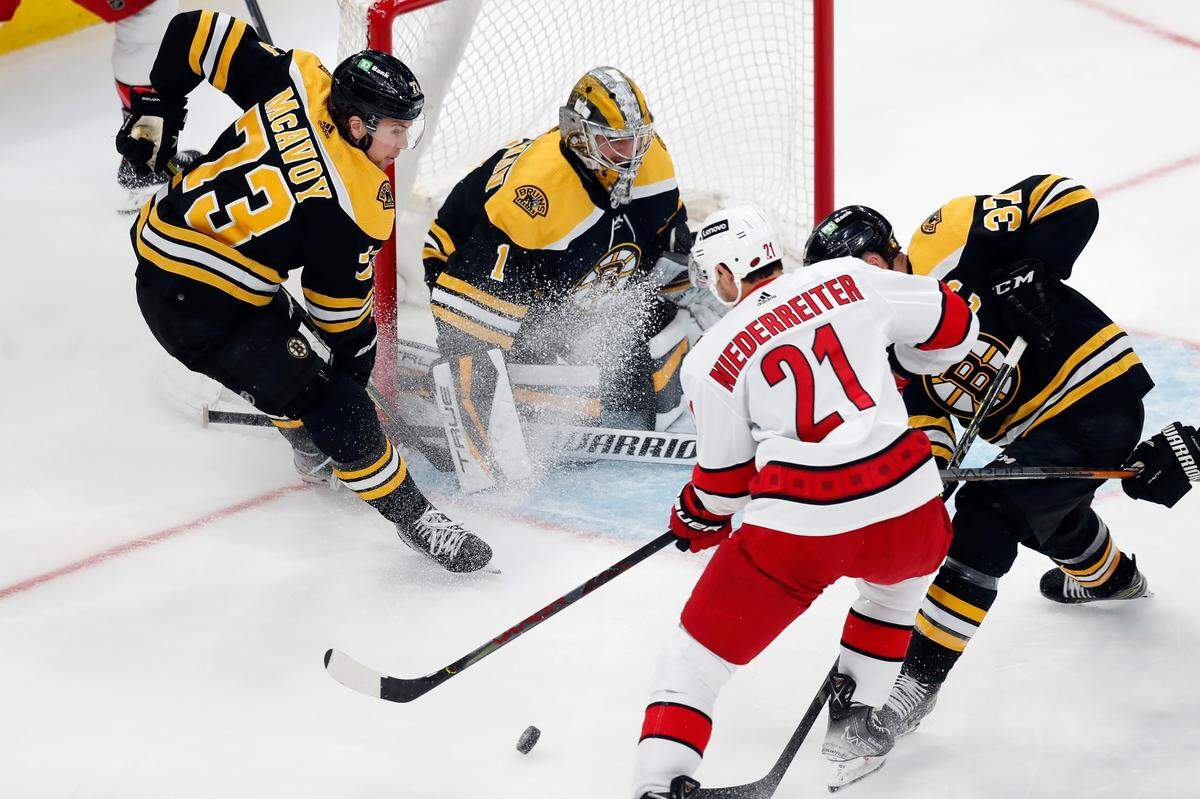 Carolina Hurricanes’ Nino Niederreiter (21) works against Boston Bruins’ Patrice Bergeron (37) in front of goalie Jeremy Swayman (1) during the first period in Game 6 of an NHL hockey Stanley Cup first-round playoff series Thursday, May 12, 2022, in Boston. (AP Photo/Michael Dwyer)