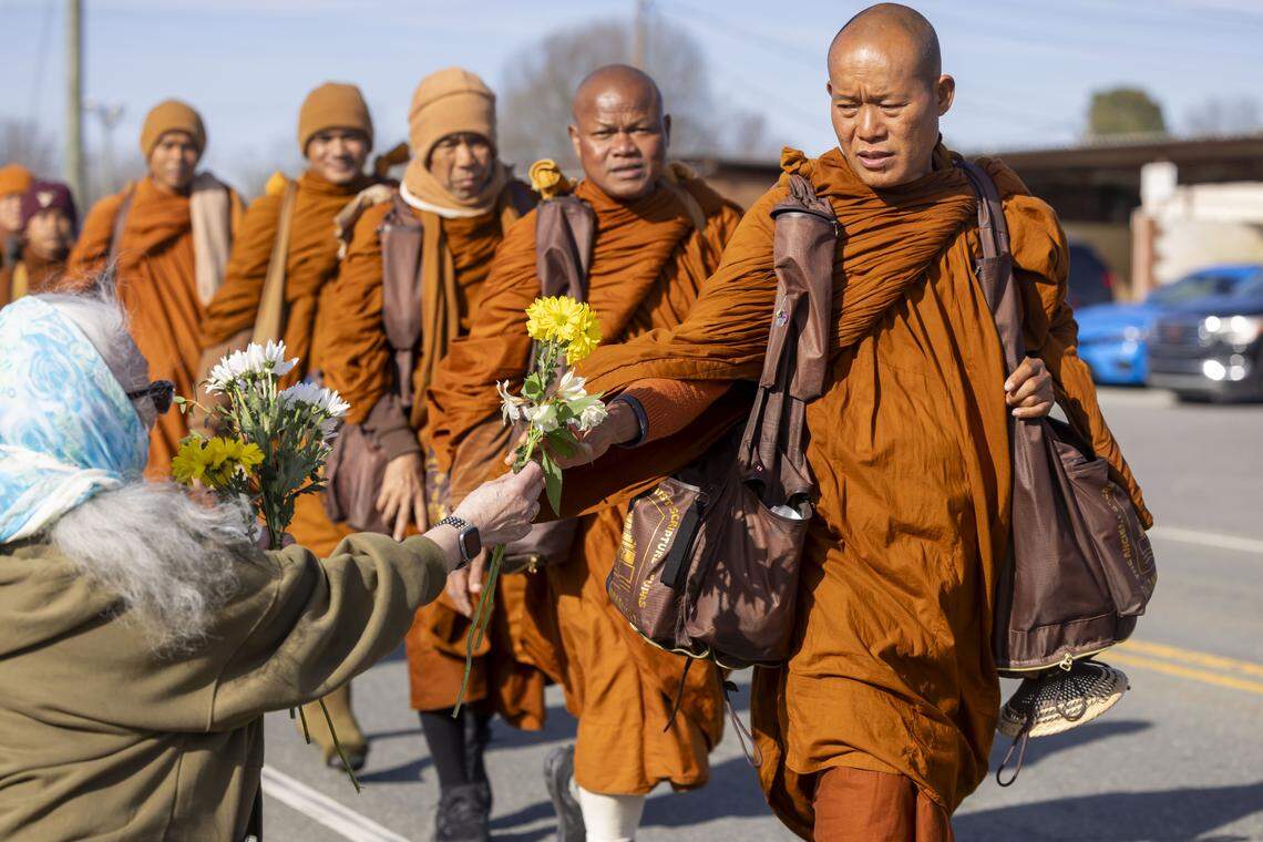 Buddhist Monks accept flowers from spectators, during their Walk for Peace, on Wednesday in Liberty, N.C.