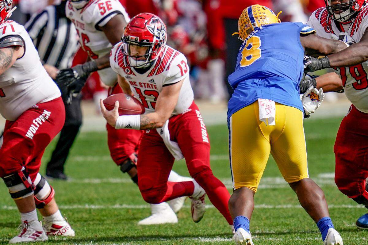North Carolina State quarterback Devin Leary (13) scrambles for a first down past Pittsburgh defensive lineman Calijah Kancey (8) during the second half of an NCAA college football game, Saturday, Oct. 3, 2020, in Pittsburgh. North Carolina State won 30-29.