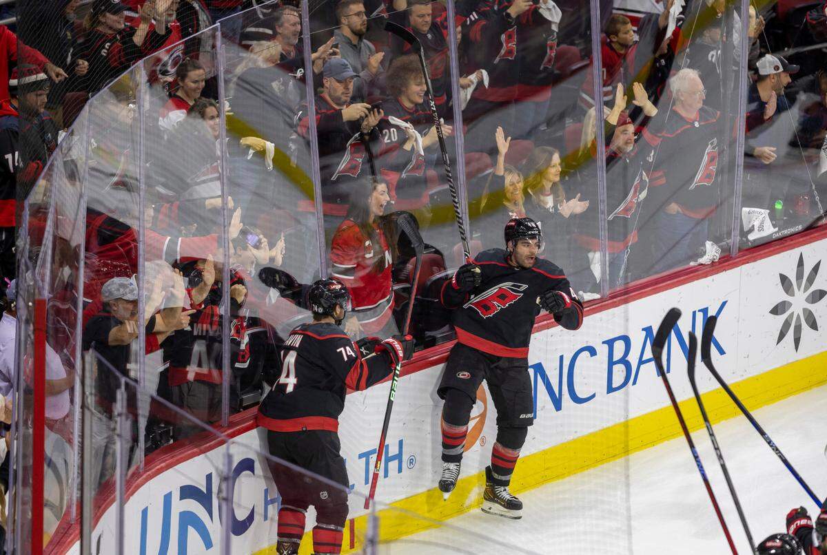 The Carolina Hurricanes Jordan Martinook (48)l and Jaccob Slavin (74) crash the boards as they celebrate their 5-3 victory over Ottawa on Wednesday, October 11, 2023 at PNC Arena, in Raleigh N.C.