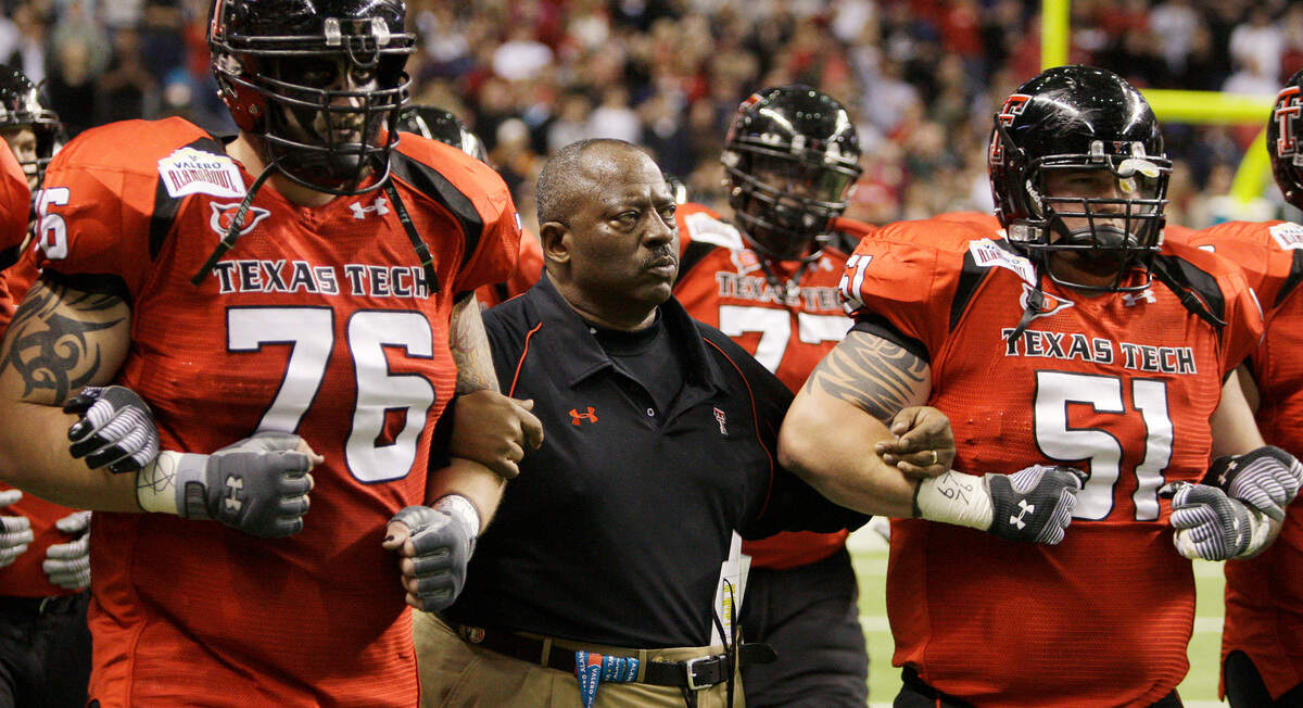 Texas Tech interim coach Ruffin McNeill, center, walks arm-in-arm with players prior to their Alamo Bowl NCAA football game against Michigan State in San Antonio, Saturday, Jan. 2, 2010. McNeill is coaching in place of Mike Leach who was fired by Texas Tech earlier this week.