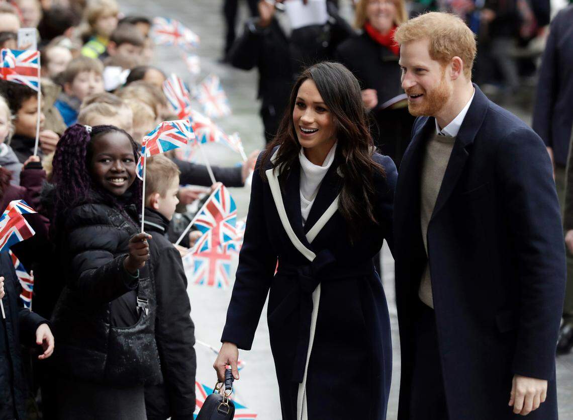 Britain's Prince Harry and his fiancee, Meghan Markle, are greeted by flag-waving schoolchildren as they arrive to take part in an event for young women as part of International Women's Day in Birmingham, central England, on March 8, 2018.