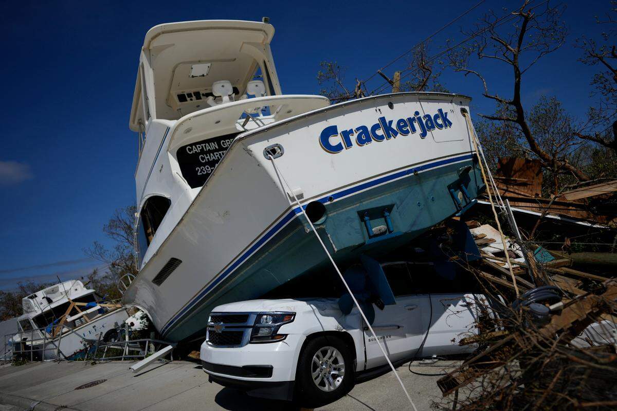 A boat displaced by Hurricane Ian rests atop a car in Fort Myers Beach, Fla., Thursday, Sept. 29, 2022.