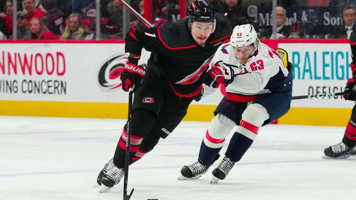Apr 5, 2024; Raleigh, North Carolina, USA; Carolina Hurricanes defenseman Dmitry Orlov (7) skates with the puck past Washington Capitals left wing Ivan Miroshnichenko (63) during the first period at PNC Arena. Mandatory Credit: James Guillory-USA TODAY Sports