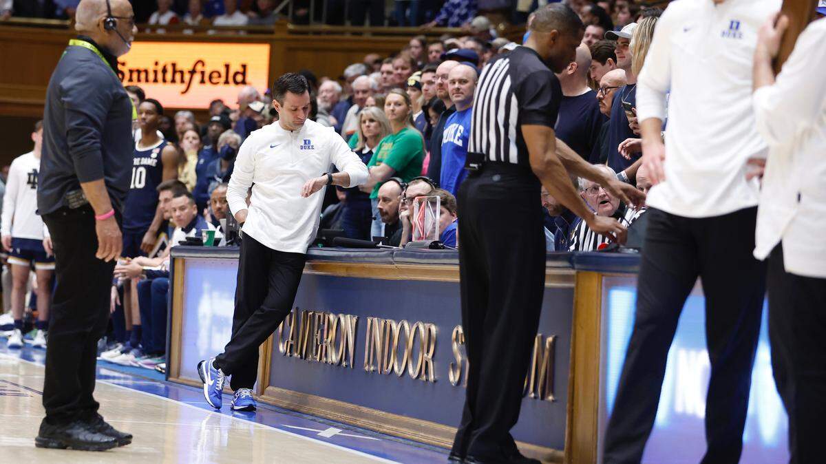 Mike DeGeorge, Duke’s former executive director of communications, checks his watch as official Ted Valentine looks over a replay during Duke’s 68-64 victory over Notre Dame at Cameron Indoor Stadium in February 2023.