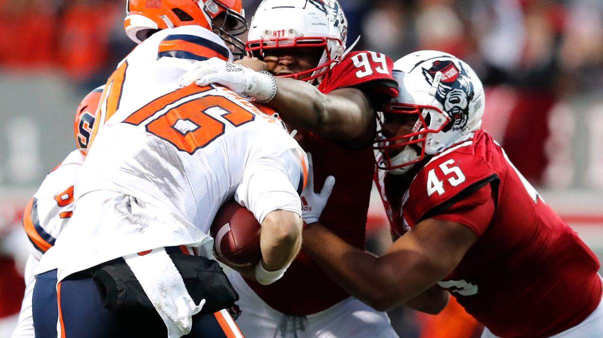 N.C. State’s Daniel Joseph (99) and Davin Vann (45) sack Syracuse quarterback Garrett Shrader (16) during the first half of N.C. State’s game against Syracuse at Carter-Finley Stadium in Raleigh, N.C., Saturday, Nov. 20, 2021.