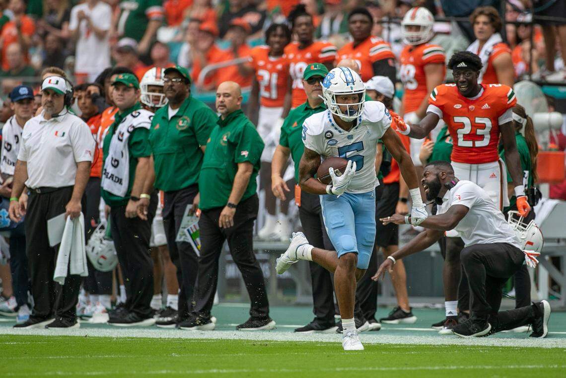 North Carolina J.J. Jones (5) races for a 74-yard touchdown in front of the Miami bench, on a pass from North Carolina quarterback Drake Maye (10) to take a 7-0 lead in the first quarter on Saturday, October 8, 2022 at Hard Rock Stadium in Miami Gardens, Florida.