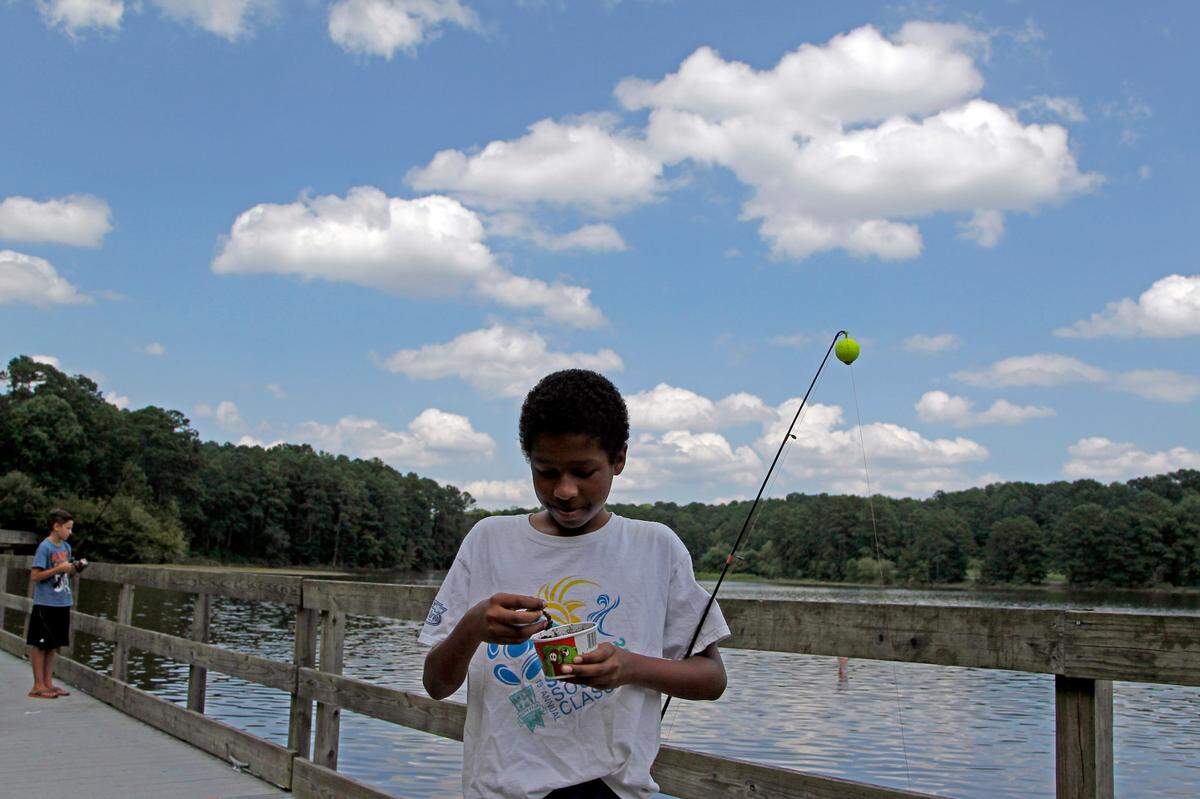 Joe Weller baits his hook under a beautiful blue sky filled with puffy clouds as he and his friend Camden Schiman, left, try their luck at Shelley Lake in Raleigh in a July 2014 file photo. They were there with Joe’s mom, Judy Weller.