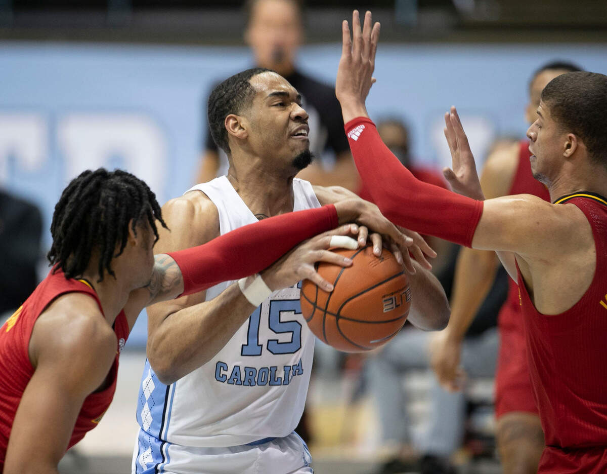 Louisville’s Dre Davis (14) and Samuel Williamson (10) defend North Carolina’s Garrison Brooks (15) during the first half on Saturday, February 20, 2021 at the Smith Center in Chapel Hill, N.C.
