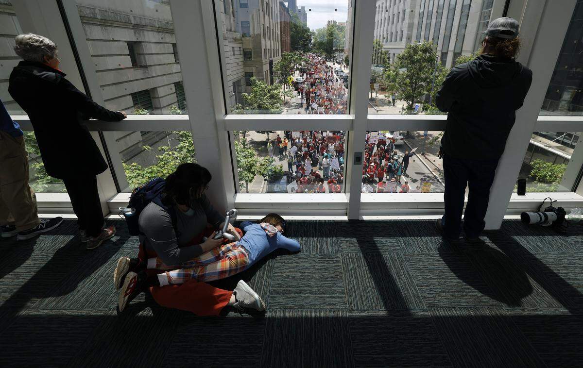 People watch from the bridge between the North Carolina Museum of Natural Sciences and the Nature Research Center as thousands march down N. Salisbury St. in downtown Raleigh during a rally and march to protest for more school funding Friday, May 1, 2026. 