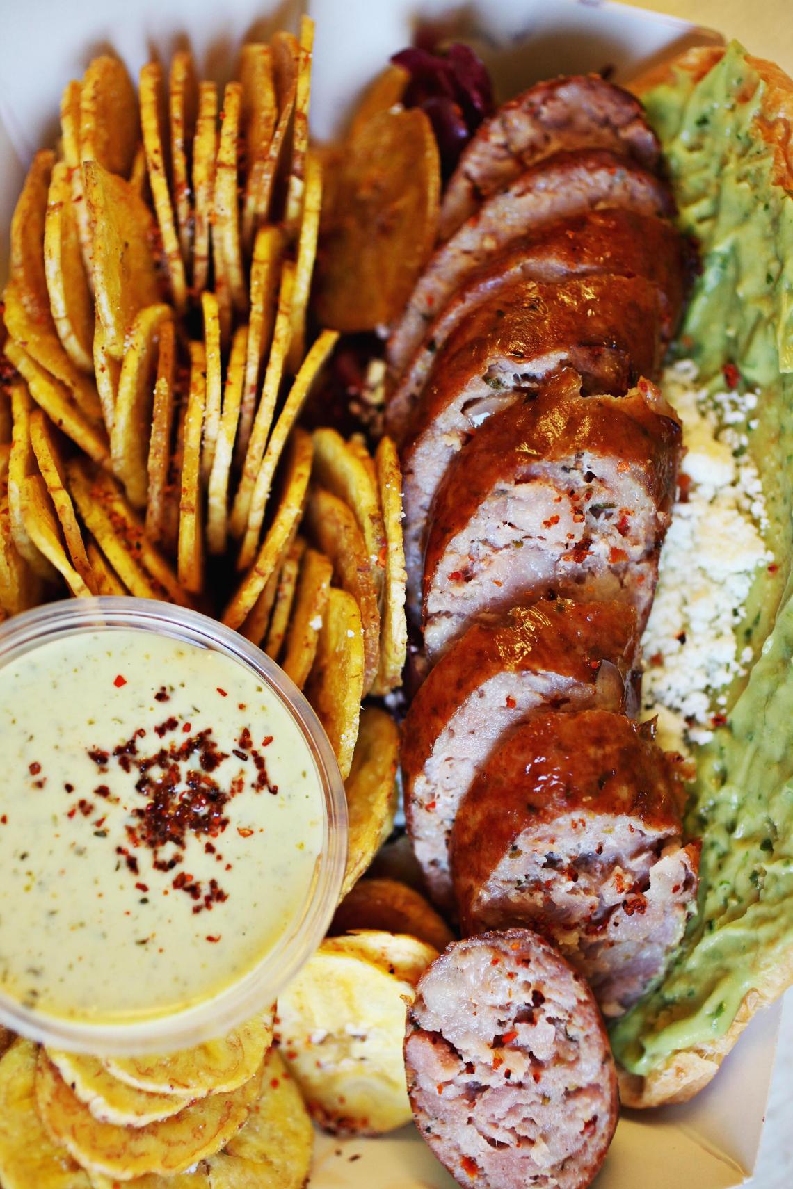 The Mestizo sandwich features Argentinean pork sausage on a grill­pressed Mexican bolillo bun lined with guacamole, kraut and crumbled cotija cheese, the sandwich is served with plantain chips and an addictive Spanish alioli brightened with a parsley­basil­cilantro pesto for dipping.