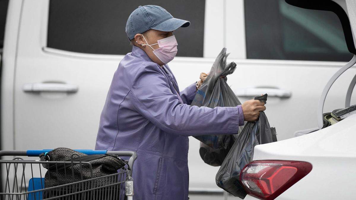 Monique Green of Garner, N.C. loads groceries and supplies into her car at the Walmart in Garner, N.C. on Monday, March 23, 2020. Green is immune deficient and elects to wear a mask when she ventures out of her home in the wake of the spread of the COVID-19 virus.