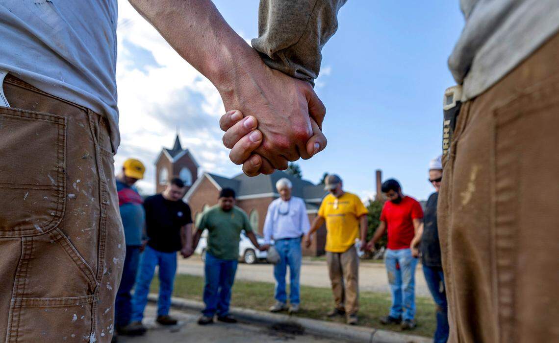 Members of IChurch from Hickory, N.C. pray with Bob Smith, center, a Trustee of the Old Fort United Methodist Church on Saturday, October 5, 2024 in Old Fort, N.C.