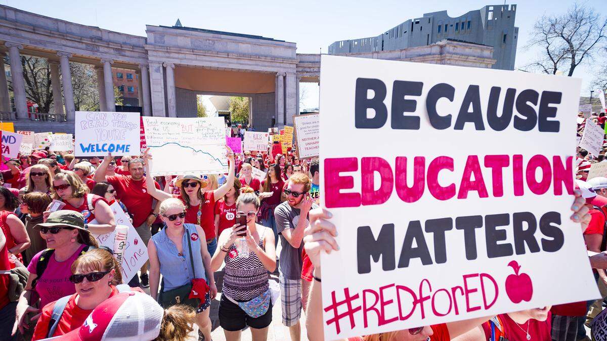 A sign reads "Because education matters, #redfored" as thousands of teachers and supporters begin their rally from the amphitheater at Civic Center Park in Denver, Colo., on Friday, April 27, 2018. About 2,000 teachers went to the Capitol on Thursday and up to 10,000 people were expected at Friday's events.  North Carolina public school teachers plan a similar demonstration in Raleigh when the legislature convenes on May 16.