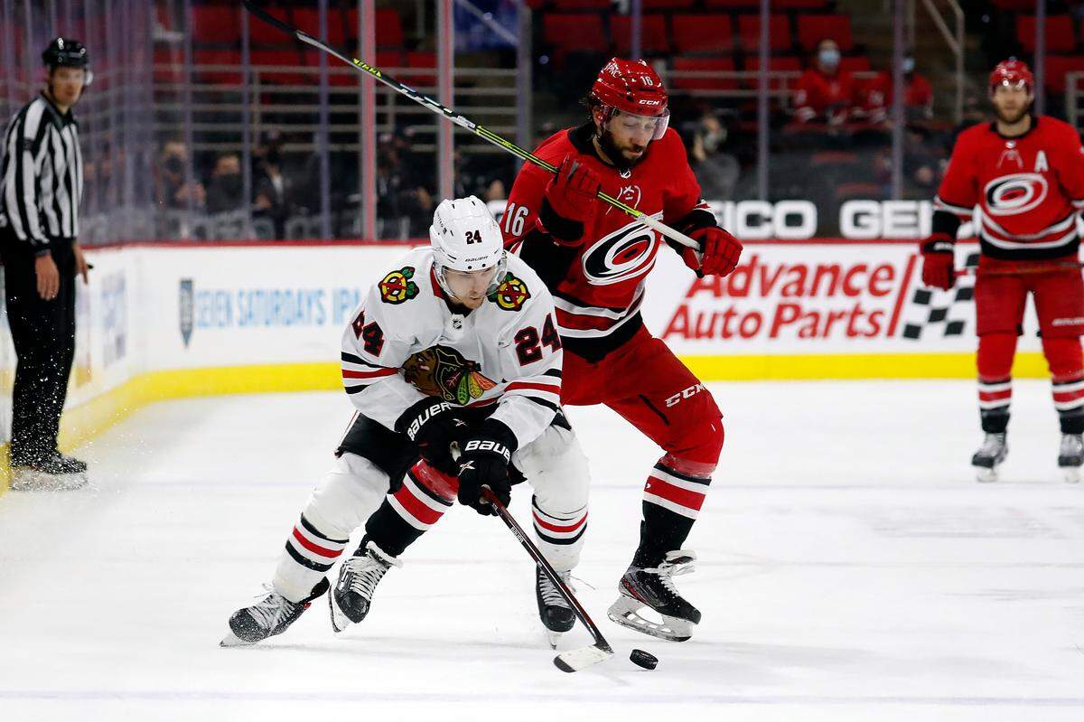 Chicago Blackhawks’ Pius Suter (24) and Carolina Hurricanes’ Vincent Trocheck (16) battle for the puck during the third period of an NHL hockey game in Raleigh, N.C., Thursday, May 6, 2021. (AP Photo/Karl B DeBlaker)