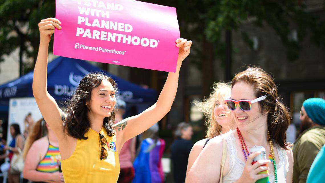 Sydney Lujan (left) of Durham is pictured holding an “I Stand For Planned Parenthood” sign while walking along Fayetteville Street at the Out! Raleigh Pride festival in downtown Raleigh on Saturday, June 25, 2022.