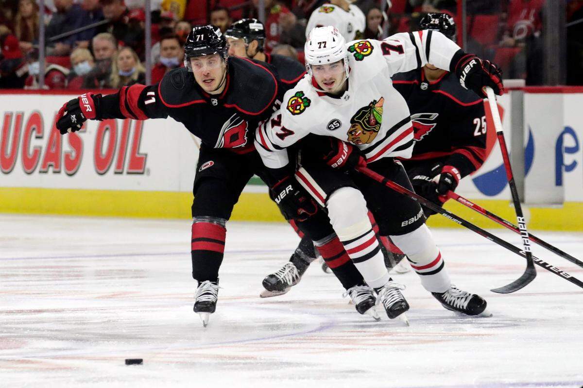 Carolina Hurricanes right wing Jesper Fast (71) and Chicago Blackhawks center Kirby Dach (77) chase the puck during the first period of an NHL hockey game Friday, Oct. 29, 2021, in Raleigh, N.C. (AP Photo/Chris Seward)