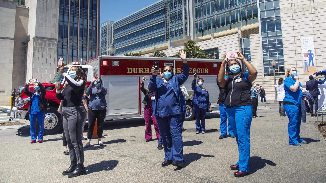 Duke University Hospital staff wave to the Life Flight helicopter circling overhead during a parade of Durham area first responders who circled the hospital to thank healthcare workers on the frontlines during the coronavirus pandemic, on Monday, Apr. 27, 2020, in Durham, N.C.