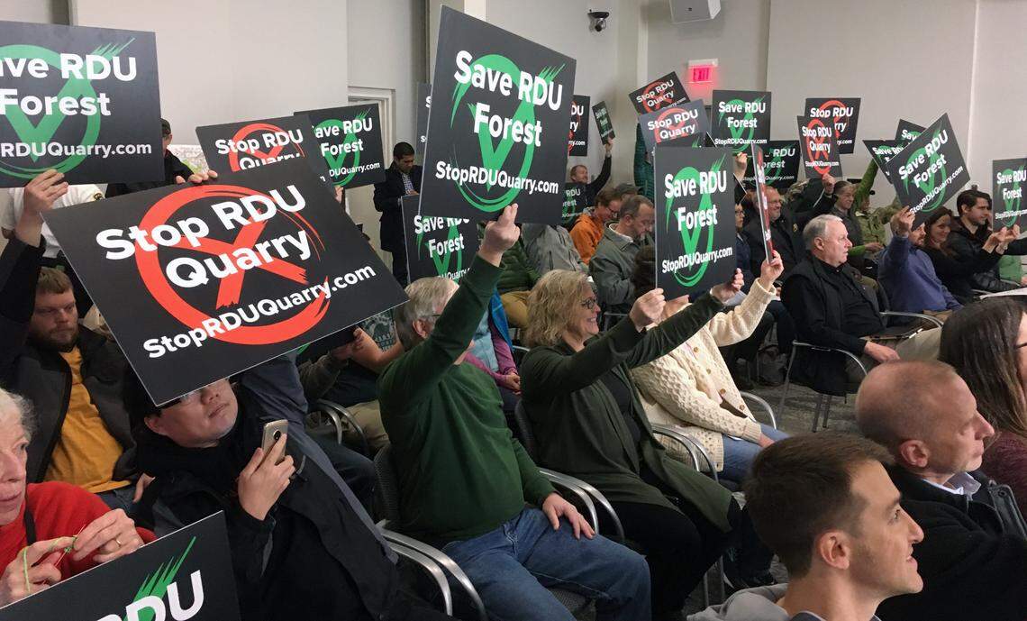 Members of the audience for a 2019 meeting of the Raleigh-Durham Airport Authority show their feelings, before the board voted to make 105 acres of airport land available for a quarry.