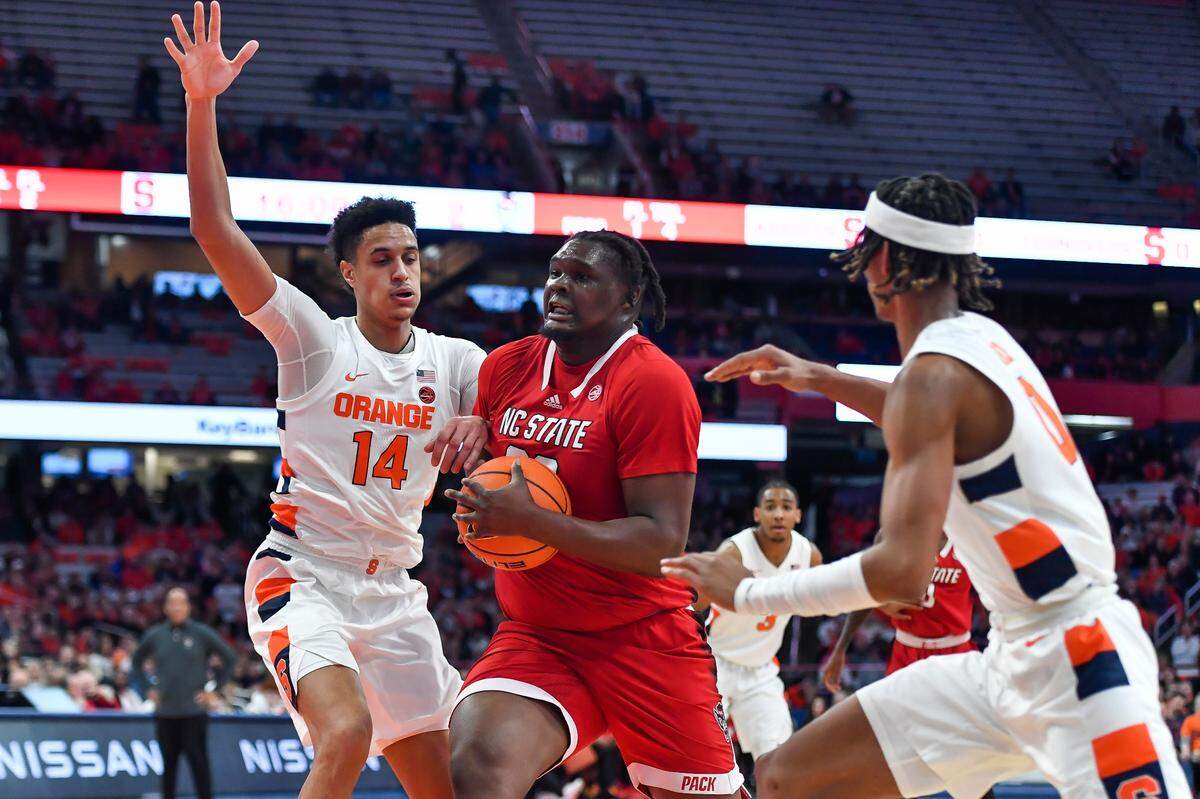 North Carolina State forward DJ Burns, Jr., center, splits the defense of Syracuse center Jesse Edwards (14) and forward Chris Bell during the first half of an NCAA college basketball game in Syracuse, N.Y., Tuesday, Feb. 14, 2023. (AP Photo/Adrian Kraus)