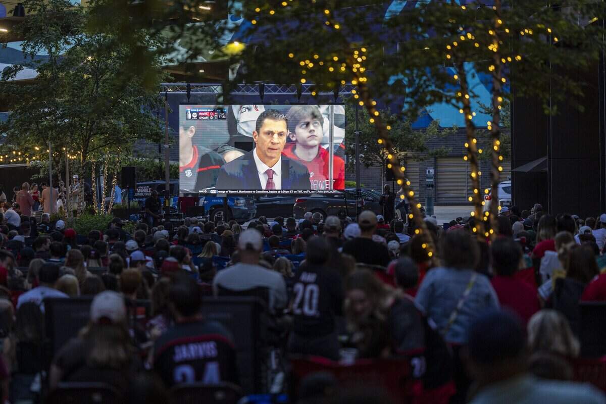 Carolina Hurricanes fans watch a large video screen during an NHL Eastern Conference Final watch party in Raleigh's Smoky Hollow district on Friday, May 29, 2026. The Hurricanes advanced to the Stanley Cup Final with a 6-1 victory over the Montreal Canadiens at Lenovo Center in Raleigh, marking the franchise's first appearance in the NHL championship series in 20 years.