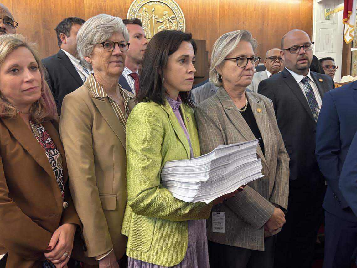 Rep. Beth Helfrich, a Mecklenburg County Democrat, holds printed copies of over 12,000 public comments submitted virtually about North Carolina Republicans’ Trump-backed proposal to draw a new congressional map favoring the GOP.
