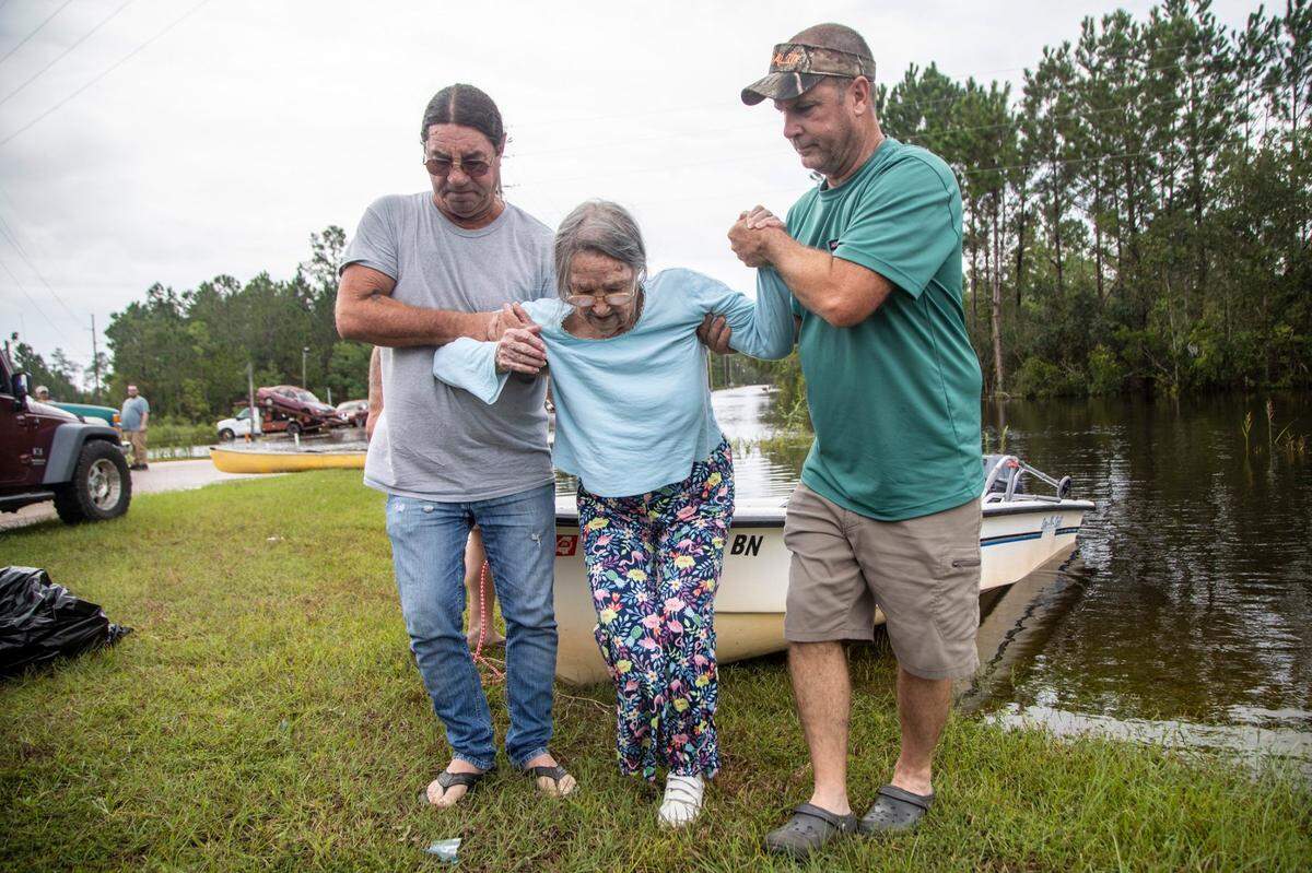 Stanley Delle, left, and Jeff Delle help 80-year-old Eileen Delle onto dry land Monday, Aug. 30, 2021 after floodwaters from Hurricane Ida surrounded her elevated home in the Shoreline Park community in Bay St. Louis.