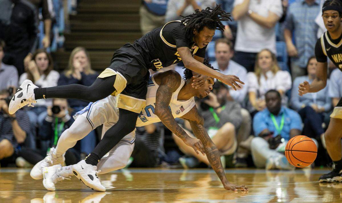 Wake Forest’s Tyree Appleby (1) dives over North Carolina’s Caleb Love (2) as they go after a loose ball in the second half on Wednesday, January 4, 2023 at the Smith Center in Chapel Hill, N.C.