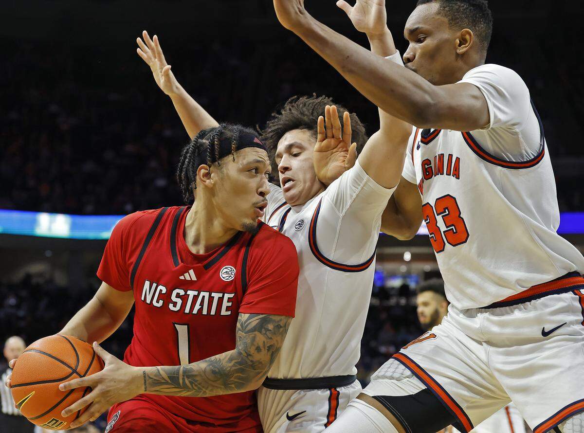 N.C. State's Darrion Williams is pressured by Virginia's Chance Mallory and Ugonna Onyenso during the second half of the Wolfpack’s 90-61 loss on Thursday, Feb. 24, 2026, at John Paul Jones Arena in Charlottesville, Va.