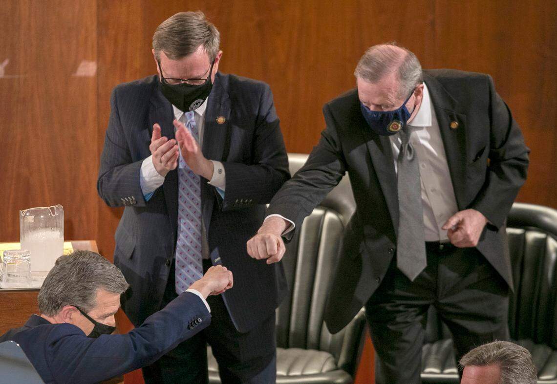 Senate leader Phil Berger fist bumps Governor Roy Cooper after Cooper delivered his State of the State address before a joint session of the North Carolina House and Senate on Monday, April 26, 2021 in Raleigh, N.C. House Speaker Tim Moore is to the left.