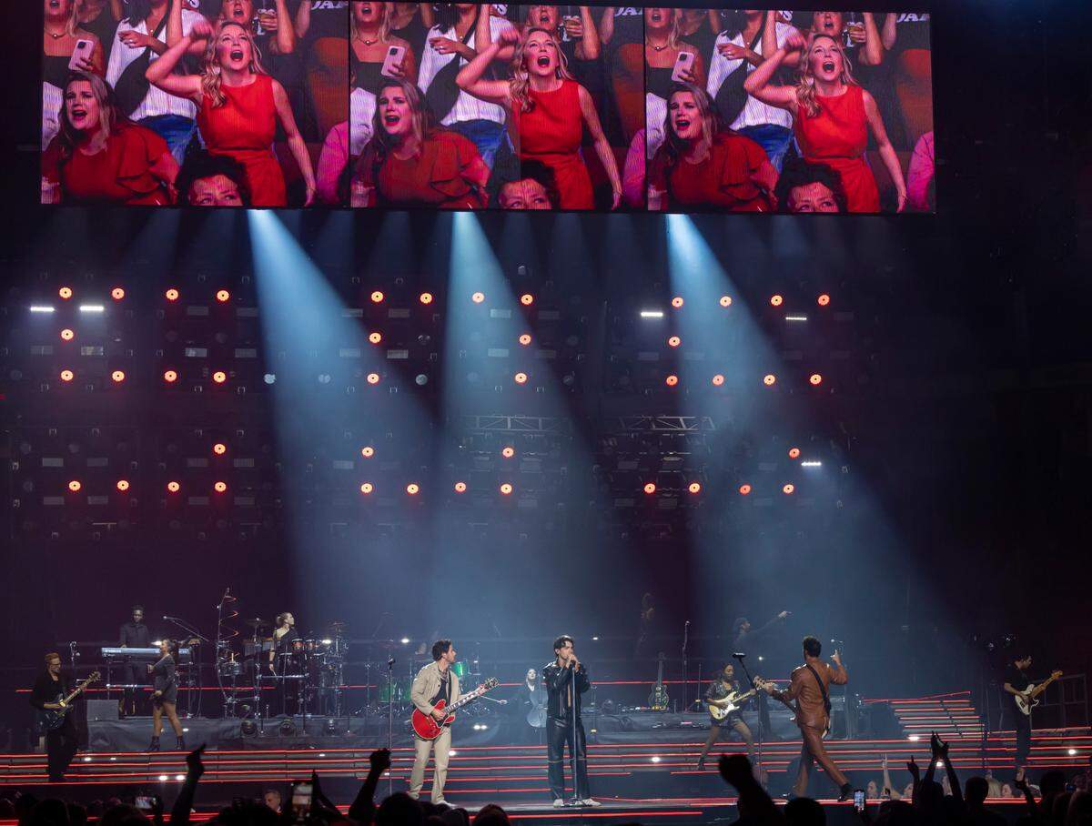 Images of enthusiastic fans are projected above the Jonas Brothers during their “Five Albums, One Night” tour stop at the PNC Arena on Thursday, September 28, 2023 in Raleigh, N.C.