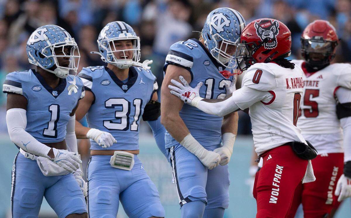 North Carolina defensive lineman Beau Atkinson (12) gets on the face of N.C. State linebacker Sean Brown (0) after a defensive stop in the first quarter on Saturday, November 30, 2024 at Kenan Stadium in Chapel Hill, N.C.