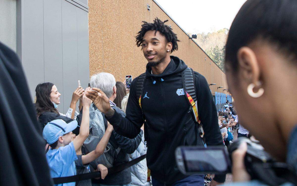 Leaky Black high-fives fans with his teammates outside the Dean Dome in Chapel Hill, N.C. as the UNC basketball team begins their journey to the Final Four in New Orleans on Wednesday, March 30, 2022.