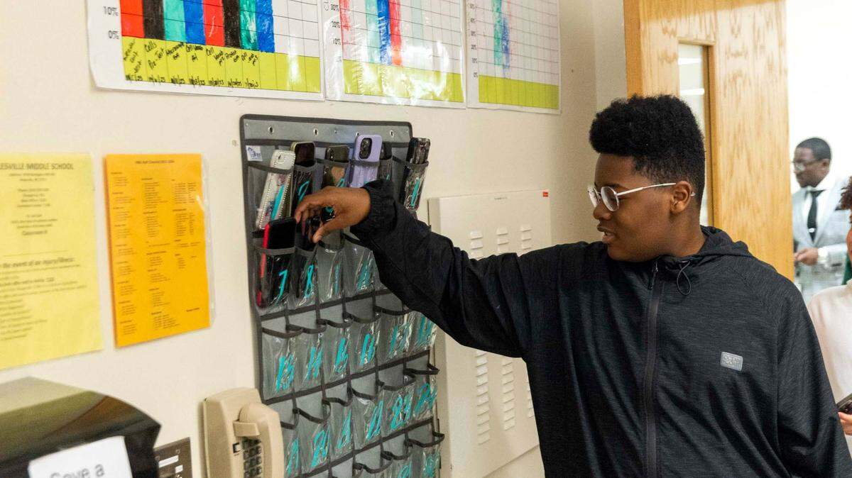 Jamaal Wellman places his phone in a caddy at the start of a seventh-grade social studies class at Rolesville Middle School on March 27, 2024. Rolesville Middle is among a growing number of schools in North Carolina and nationally that limit student access to phones when they’re in class.