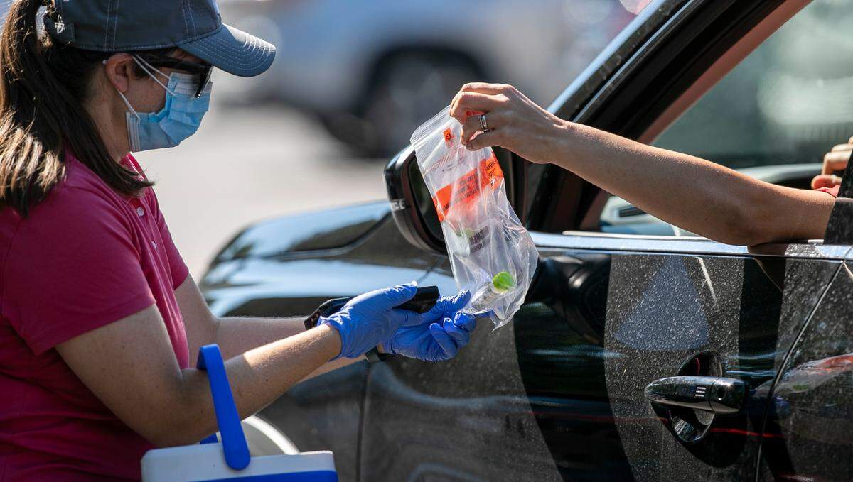 A visitor to the COVID-19 testing site on Departure Drive hands off their nasal swab to a staff member on Tuesday morning, September 7, 2021 in Raleigh, N.C. Hundreds of people filed into the testing site parking lot on Tuesday morning after being closed for two days for the Labor Day Holiday.