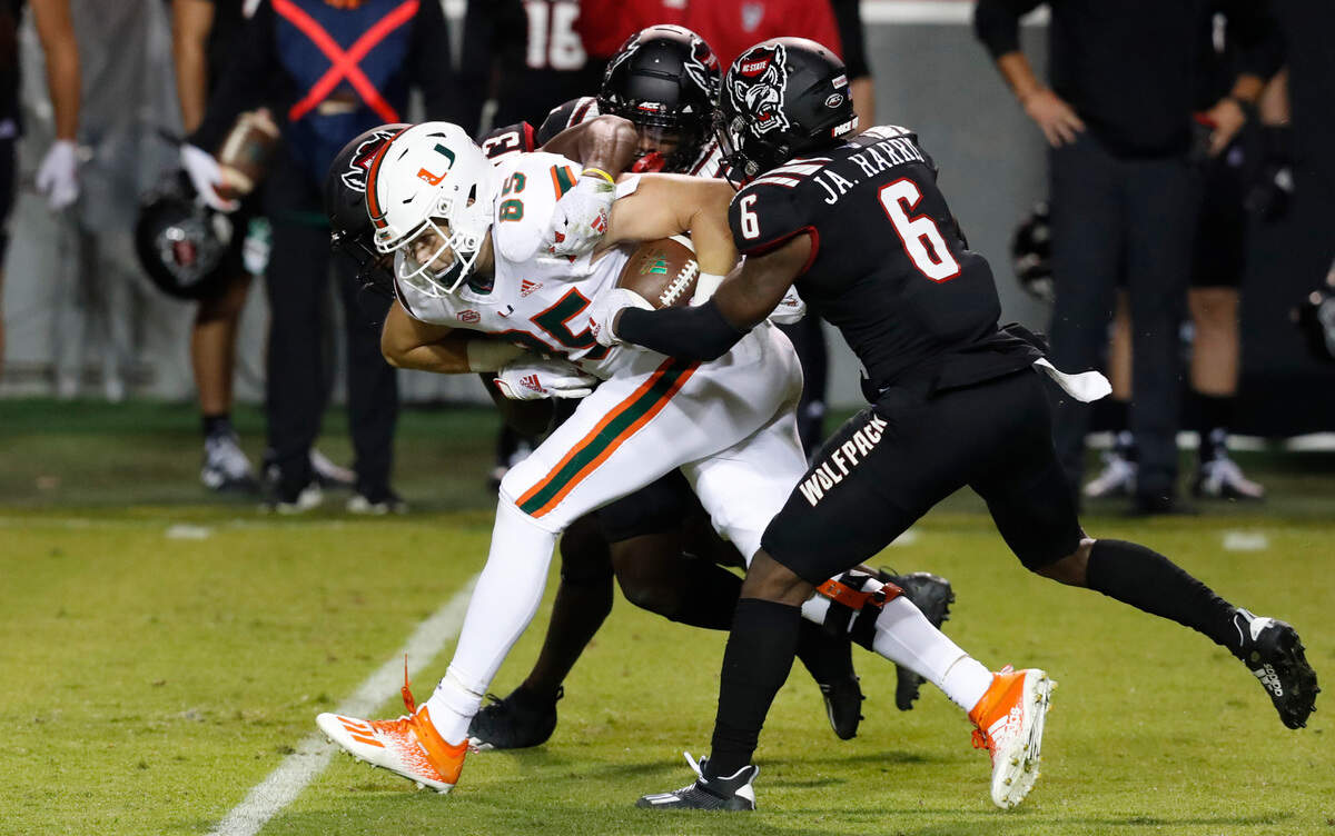Miami tight end Will Mallory (85) is tackled by N.C. State safety Jakeen Harris (6), Tyler Baker-Williams (13) and Cecil Powell (4) during the first half of N.C. State’s game against Miami at Carter-Finley Stadium in Raleigh, N.C., Friday, Nov. 6, 2020.