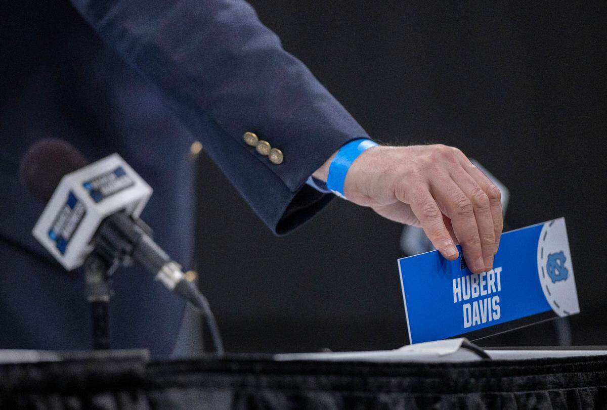 Moderator Phil Warshauer positions a name plate for North Carolina coach Hubert Davis on dais prior to his arrival for media availability for the NCAA Tournament on Wednesday, March 20, 2024 at Spectrum Center in Charlotte, N.C.