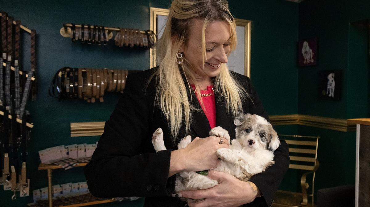 Jacklyn Barefoot, owner of Petopia, smiles while holding Paisley, an eight-week-old Aussiedoodle puppy, at her store in downtown Raleigh, N.C. on Tuesday, Jan. 14, 2025.