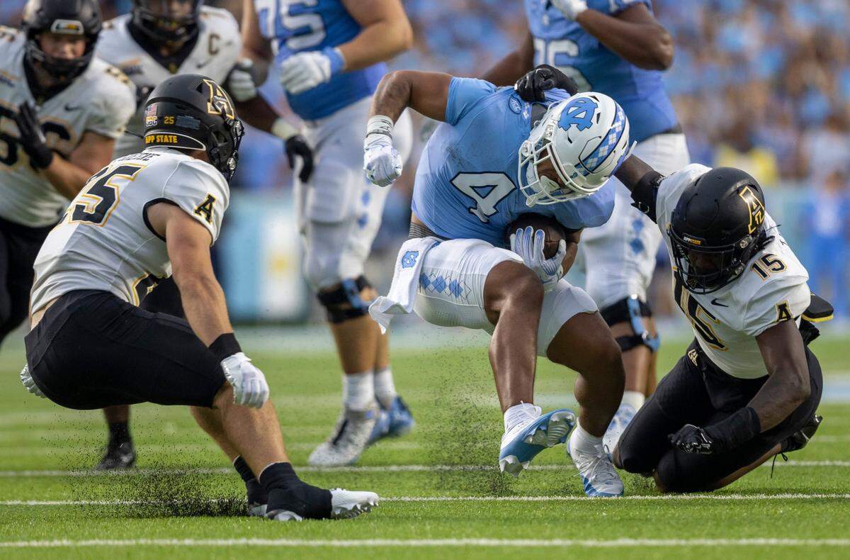 North Carolina’s Caleb Hood (4) rushes for 13 yards before being stopped by Appalachian’s Thomas Davis (15) in the second quarter on Saturday September 9, 2023 at Kenan Stadium in Chapel Hill, N.C. 