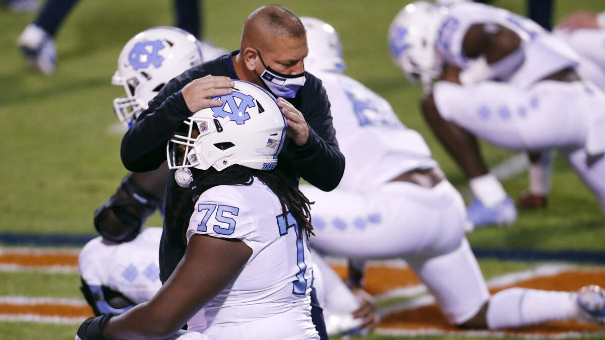UNC offensive coordinator Phil Long with offensive lineman Joshua Ezeudur (75) during warm ups before the Tar Heels’ ACC football game at Virginia Saturday night, Oct. 31, 2020.