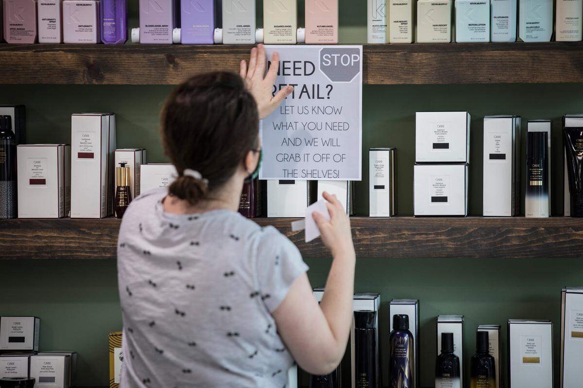 Michelle Ghassemi, owner of Meraki Salon in Raleigh, N.C., tapes up a sign about handling retail items on Thursday, May 21, 2020. Ghassemi and her employees have been preparing to open at 50% capacity since Governor Roy Cooper announced on Wednesday that hair salons are included in Phase Two of re-opening North Carolina.