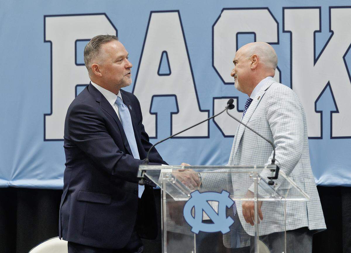 New North Carolina men’s basketball head coach Michael Malone shakes hands with incoming athletic director Steve Newmark during a press conference at the Smith Center on Tuesday, April 7, 2026, in Chapel Hill, N.C.