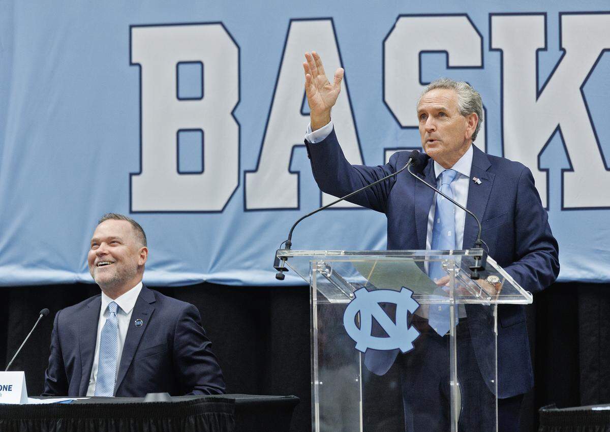 New North Carolina men’s basketball head coach Michael Malone reacts as athletic director Bubba Cunningham speaks about banners in the rafters of the Smith Center during a press conference on Tuesday, April 7, 2026, in Chapel Hill, N.C. 