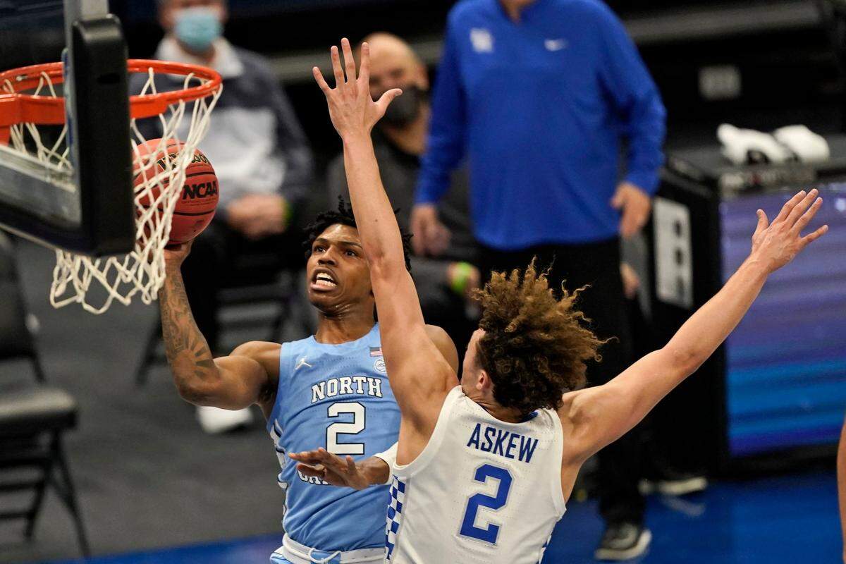 North Carolina’s Caleb Love, left, drives to the basket against Kentucky’s Devin Askew in the first half of an NCAA college basketball game, Saturday, Dec. 19, 2020, in Cleveland.