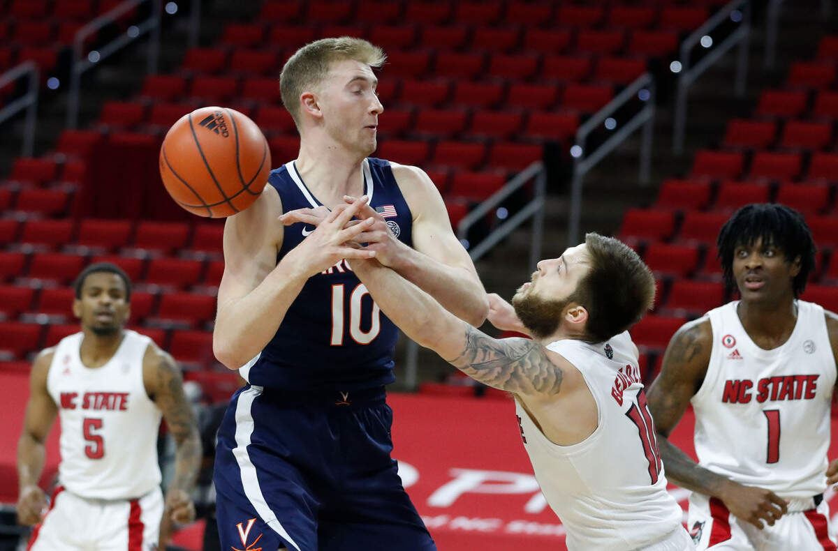 N.C. State’s Braxton Beverly (10) knocks the ball from Virginia’s Sam Hauser (10) during the first half of N.C. State’s game against Virginia at PNC Arena in Raleigh, N.C., Wednesday, February 3, 2021.
